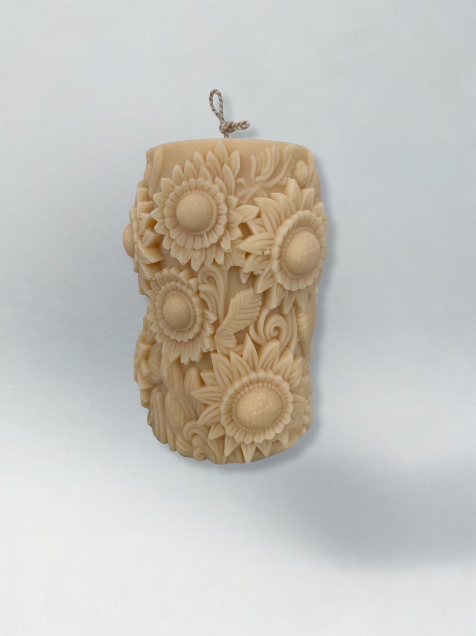 Decorative candle embossed with sunflowers with a light grey background