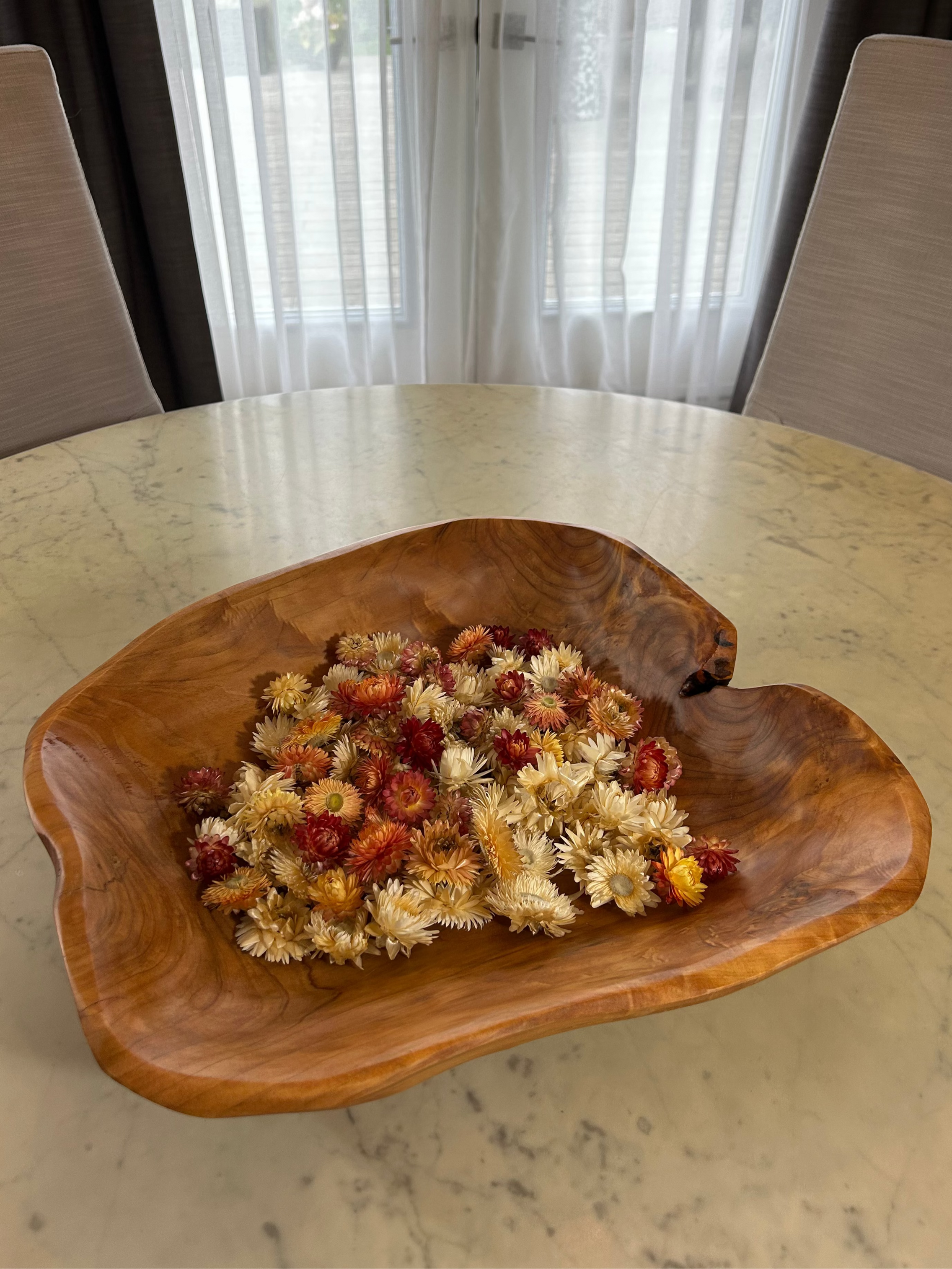 Beautiful hand carved Forest Legacy Bowl made from a fir stump left over from logging industry, filled with dried helichrysum flowers sitting on marble table.