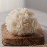 A white spherical soy wax candle embossed with a beautiful rose motif on a wooden surface.