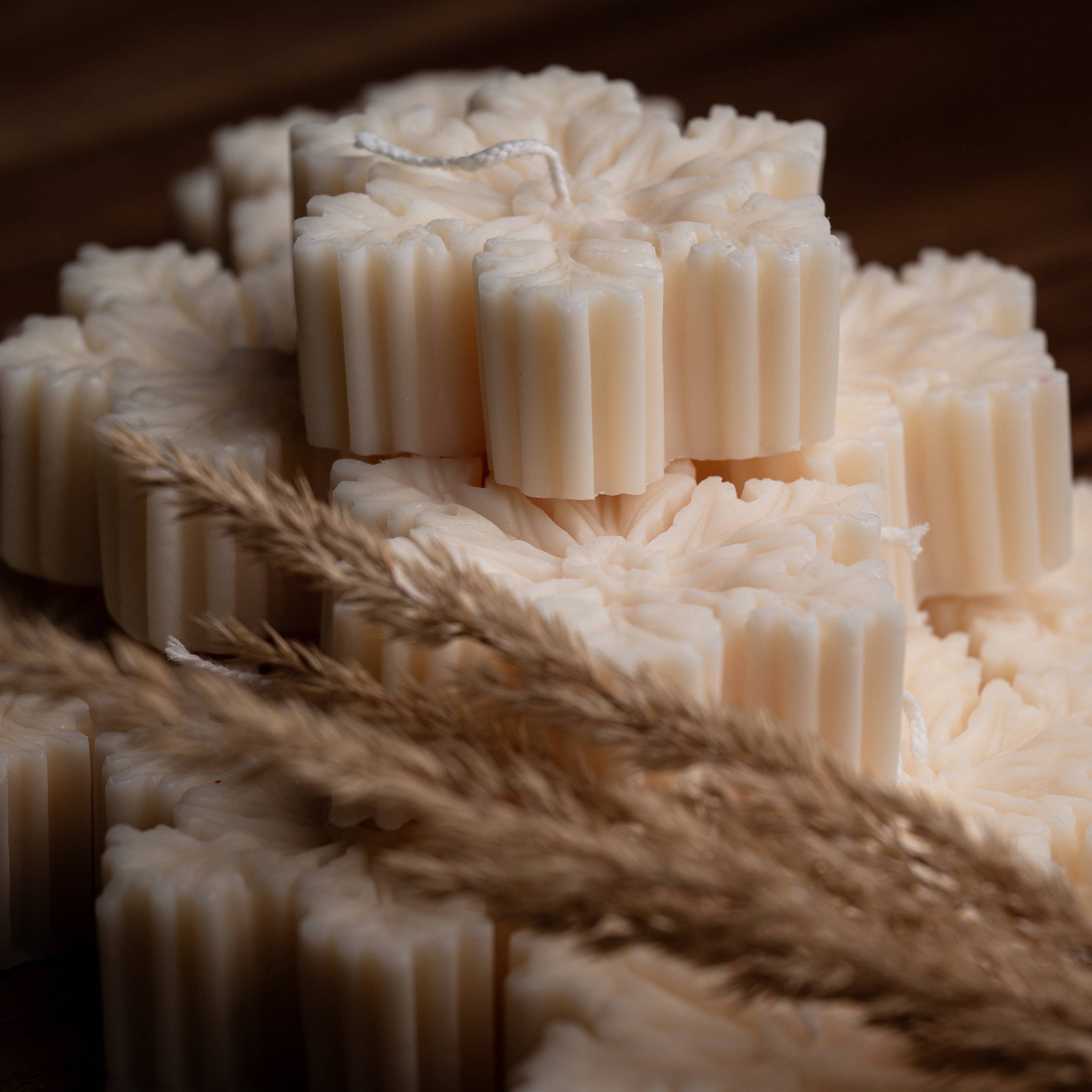 Stack of white snowflake shaped beeswax candles with a rustic background