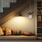 Cozy nook under a staircase with pillows, a lamp, and a bookshelf. The focal point is a white hanging planter with beautiful dried flowers arrangement with burgundy bracken, ivory helichrysums, Nigel seed pods, natural teasels, and ivory phalaris.