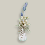 Vase of dried floral arrangement made with delicate, lace-like petals of white Cape Flowers against the intriguing, sculpted heads of blue Teasels. Adding airy lightness and enduring colour is German Statice. 