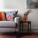 Gray sofa with colorful pillows and a small table with a beautiful dried flower arrangement in a living room setting.