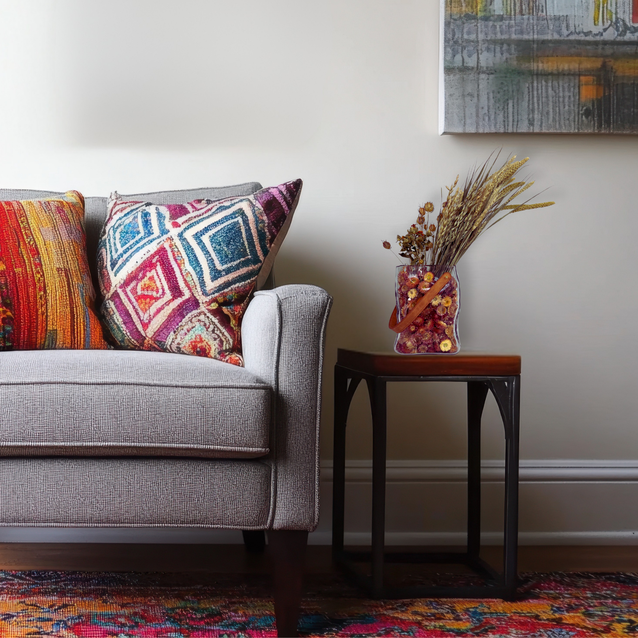 Gray sofa with colorful pillows and a small table with a beautiful dried flower arrangement in a living room setting.