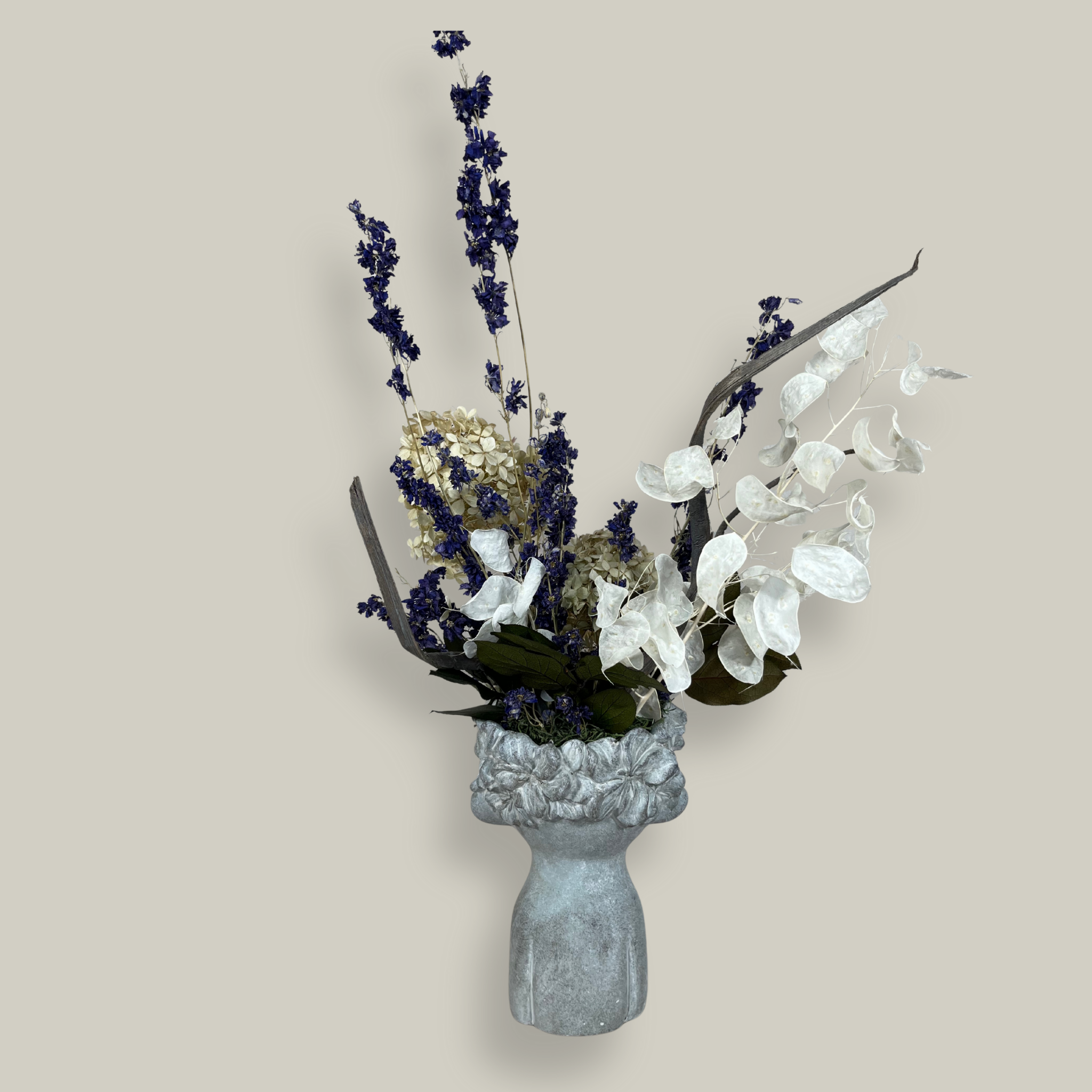 The back view of a decorative everlasting flower arrangement in a concrete vase sculpted as a woman's serene face with her lips charmingly puckered