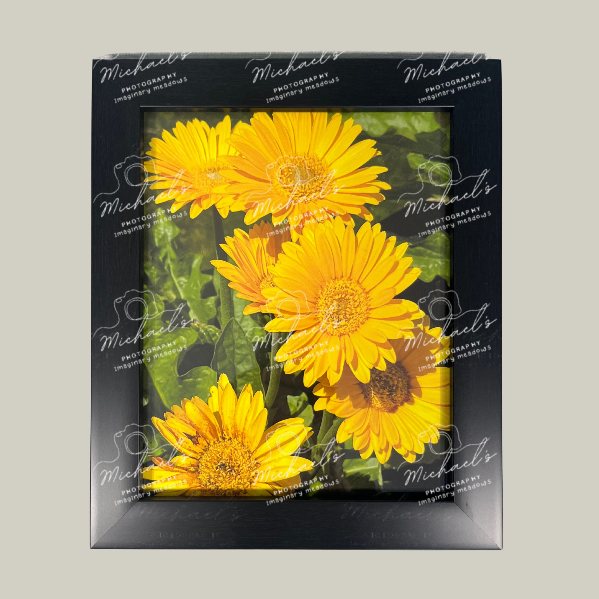 Black matte framed picture of yellow flowers with 'Michaels' branding on a gray background