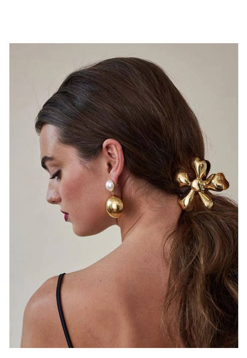 Woman with a gold hair accessory and earrings on a neutral background