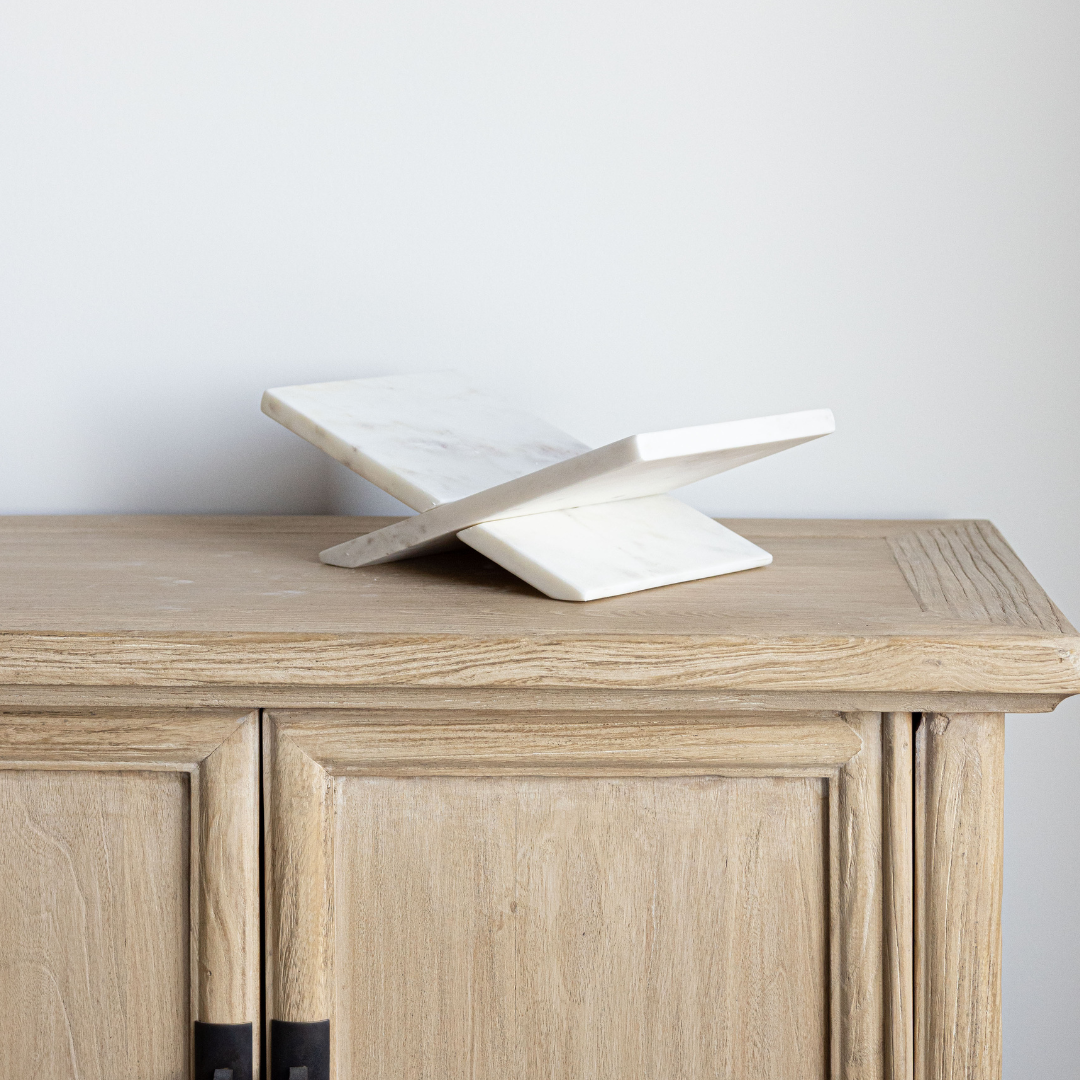 Wooden sideboard with a marble bookstand on top against a plain background
