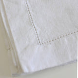 Close-up of white linen napkin with visible stitching on a light background