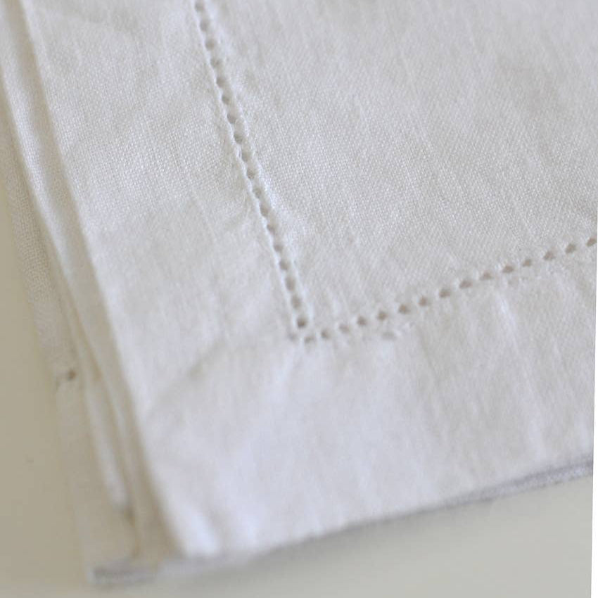 Close-up of white linen napkin with visible stitching on a light background