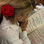Person with a red flower clip in their hair looking at a menu in a restaurant.