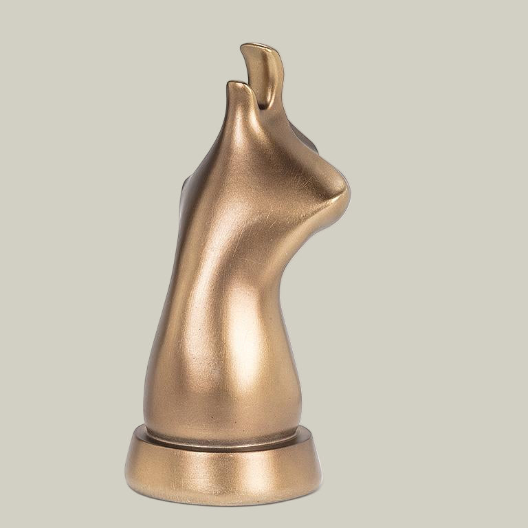 The back view of bronze coloured eye glass holder that is shaped like the lower portion of a cat's face.