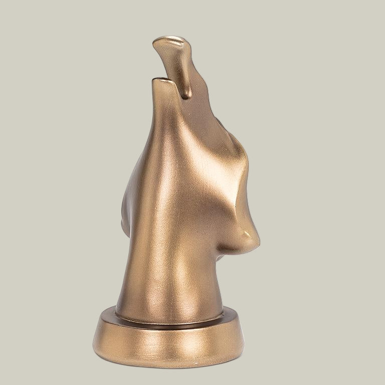 The back view of a bronze coloured eye glass holder that is shaped like the lower portion of a dog's face.