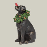 Statue of a black Labrador dog with a wreath decorated with pinecones around his neck and red cardinal on his nose.