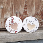 Two round bath balms with rose petals and lavender and heart shaped soap centres on a wooden surface