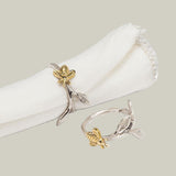 Gold and silver bee-shaped napkin rings on a white napkin.