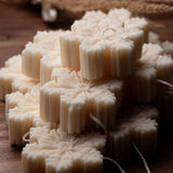 Stack of snowflake shaped white candles on a wooden surface