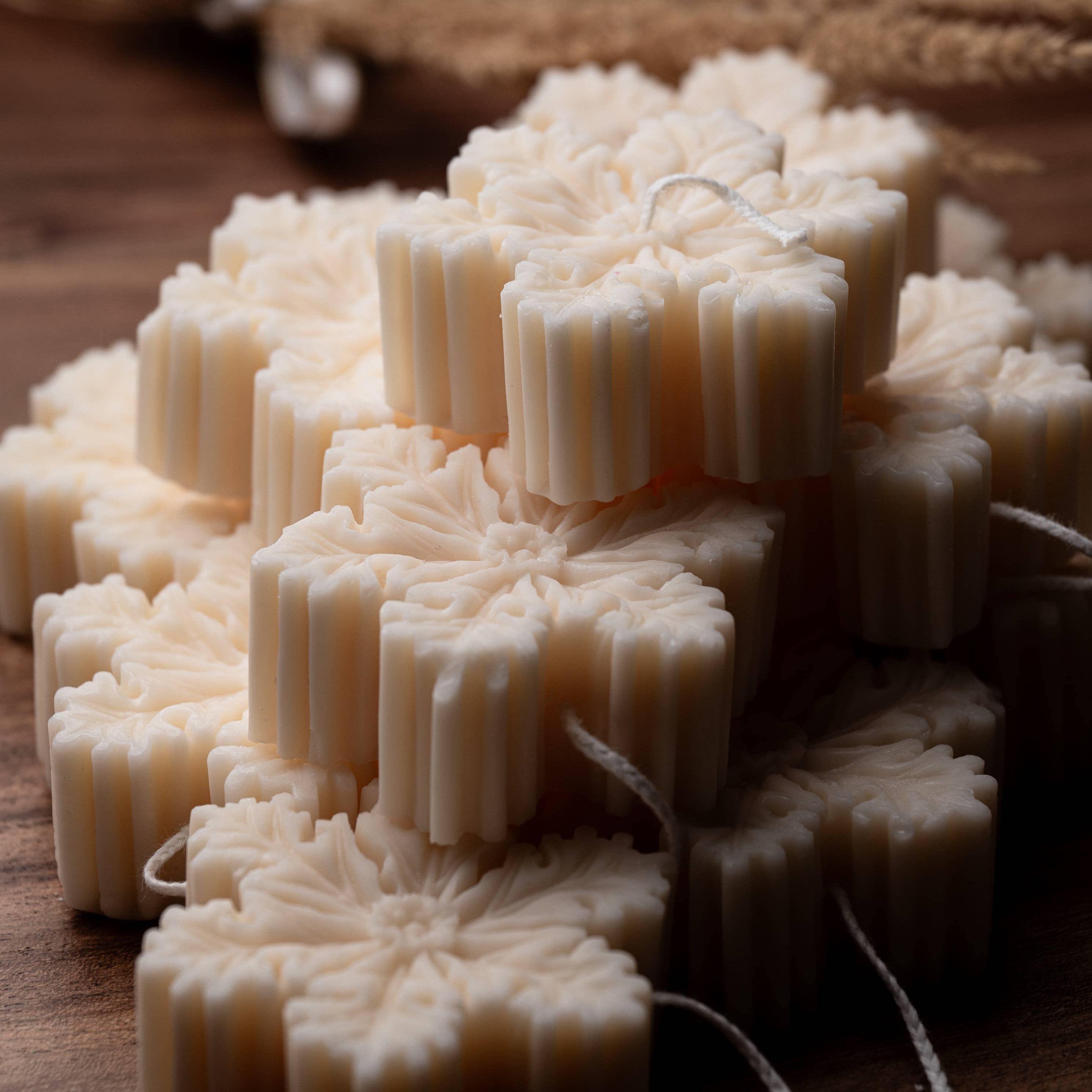 Stack of snowflake shaped white candles on a wooden surface