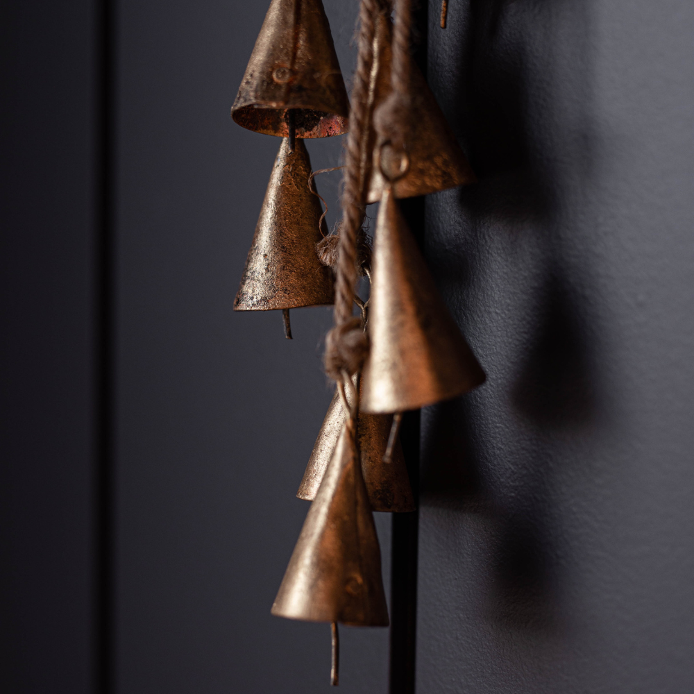 Bronze bell chime against a dark wall