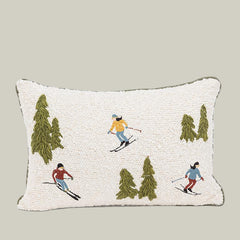Decorative pillow with embroidered skiers and trees on a white background