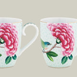 Two ceramic mugs with floral and bird design on a white background