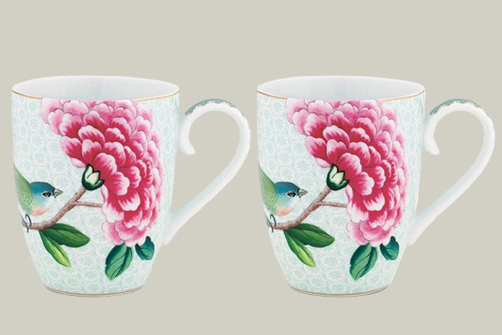 Two ceramic mugs with floral and bird design on a white background