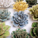 Collection of ceramic flower-shaped sculptures in various colours on a white background
