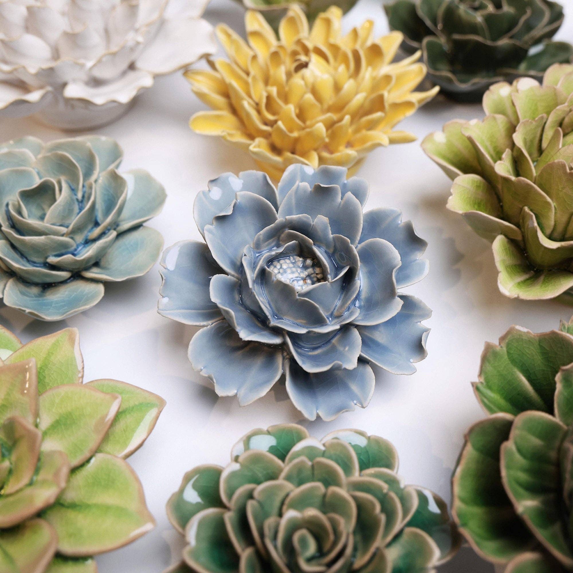 Collection of ceramic flower-shaped sculptures in various colours on a white background