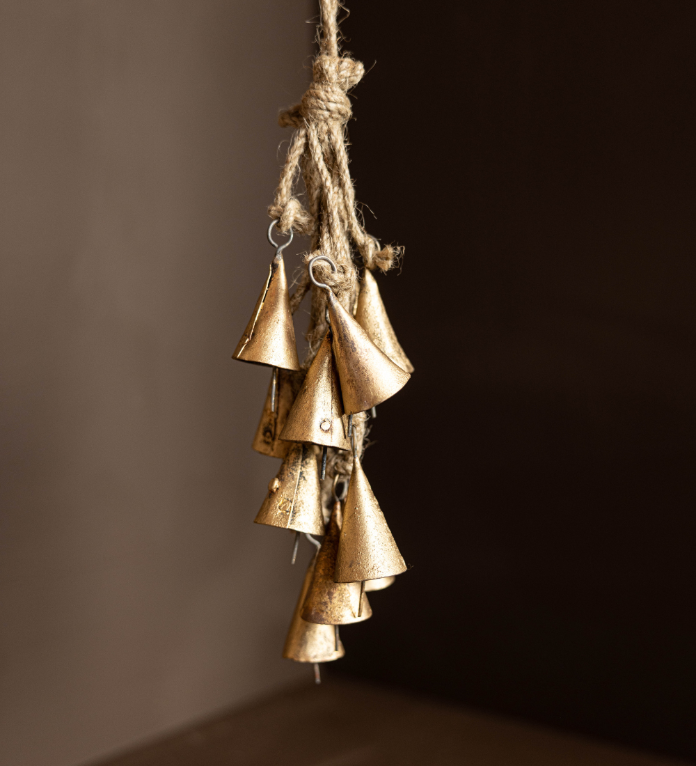 Bronze vintage inspired bells hanging on a rope against a dark background