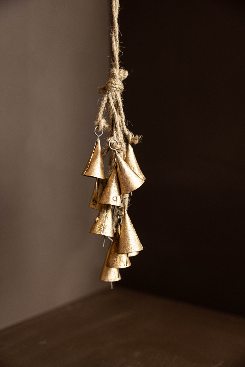 Bronze vintage inspired bells hanging on a rope against a dark background