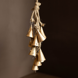 Bronze vintage inspired bells hanging on a rope against a dark background