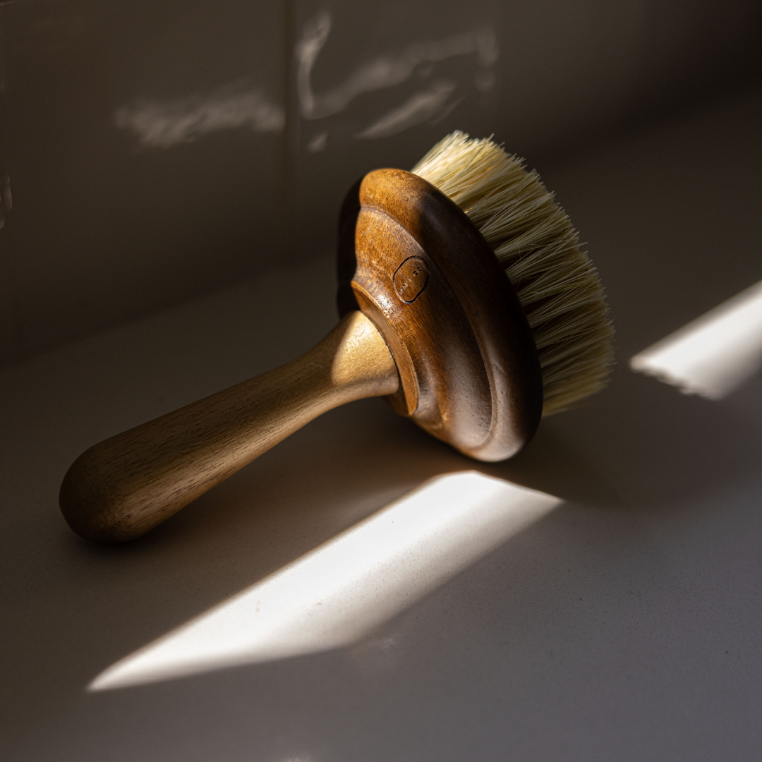 Wooden dish brush with bristles on a reflective surface