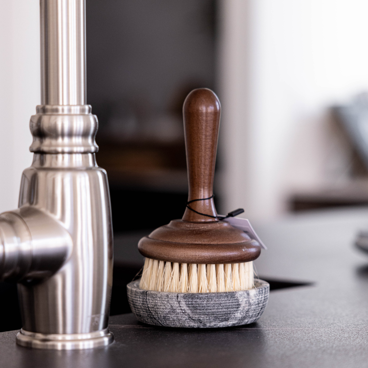 Cleaning brush with wooden handle and marble base on a dark surface