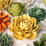 Collection of colourful ceramic flower sculptures on a light background