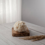A white spherical soy wax candle embossed with a beautiful rose motif on a wooden surface.