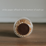 Jar of matches with a strike paper on a wooden surface