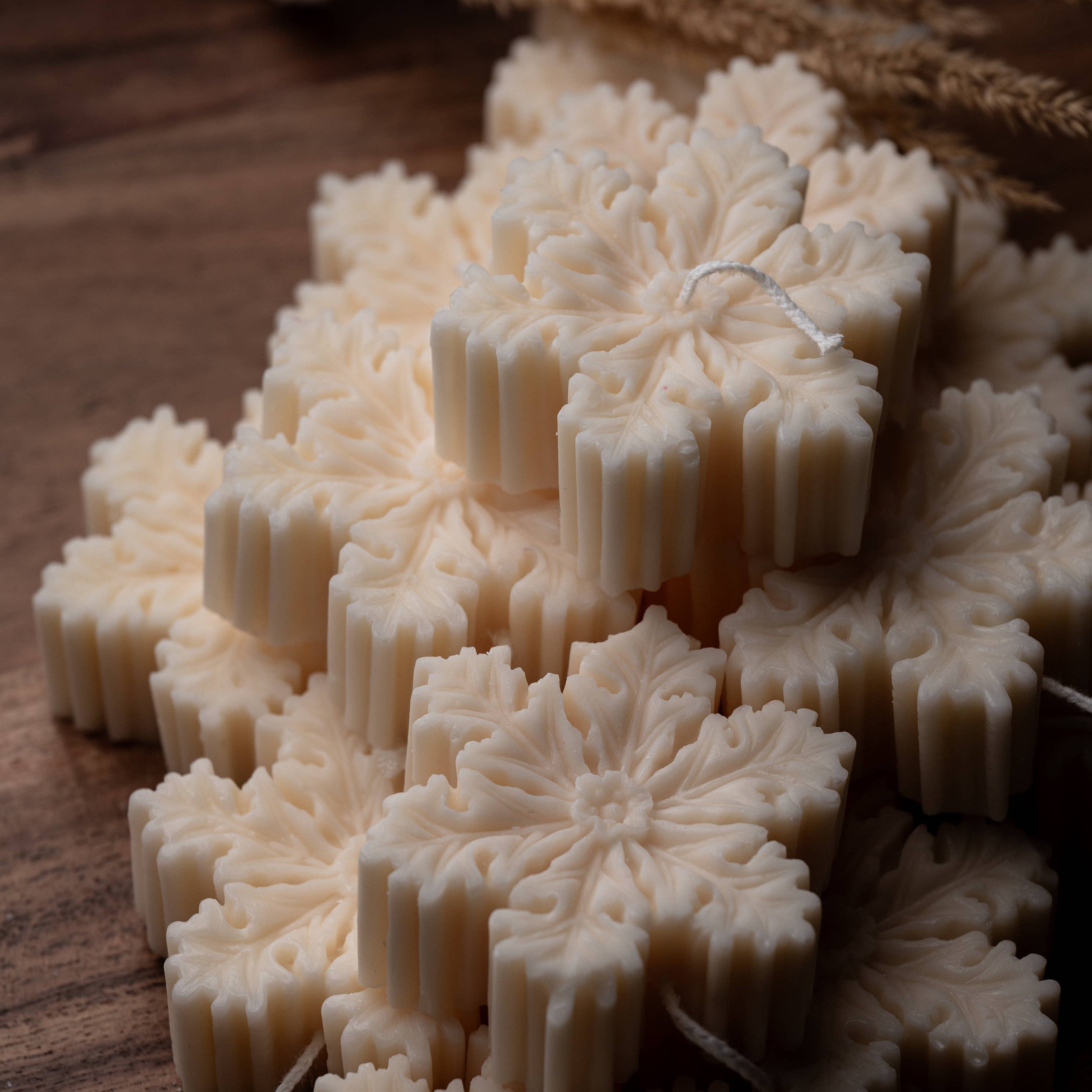 Snowflake-shaped candles on a wooden surface
