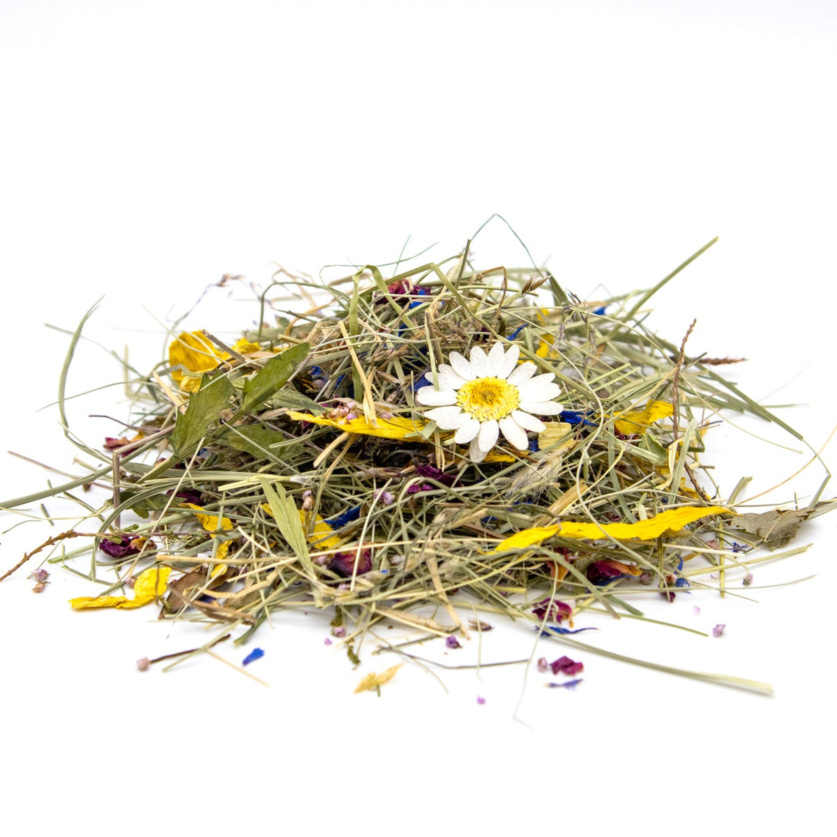 A small pile of dried botanical ingredients, including green grass-like stems, yellow pieces, and a white daisy flower, photographed on a clean white background.