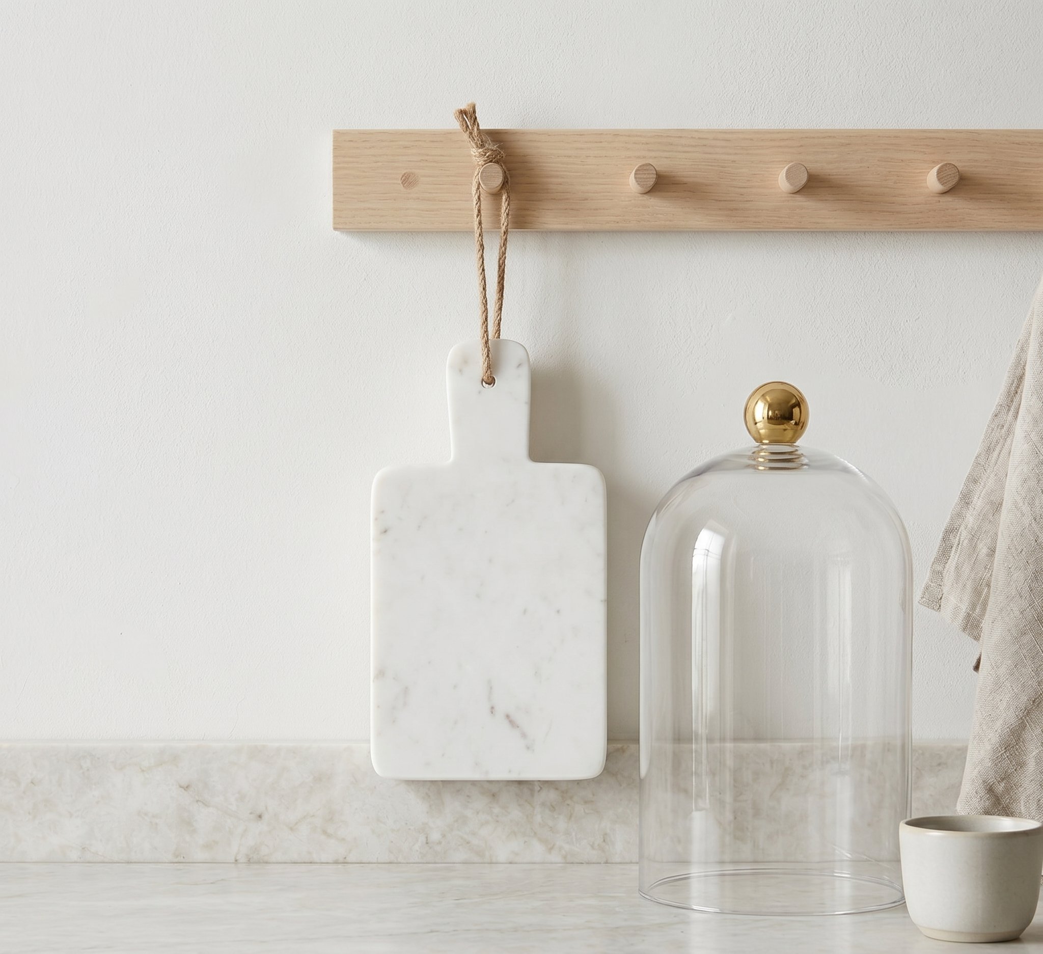 Decorative items including a marble cutting board, glass dome, and small bowl on a marble surface with a wooden pegboard in the background.