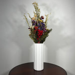 This magnificent, hand-tied bouquet is a vibrant symphony of contrasting colours and textures designed for the sophisticated interior. Seen here in a vibrant white ceramic vase. 