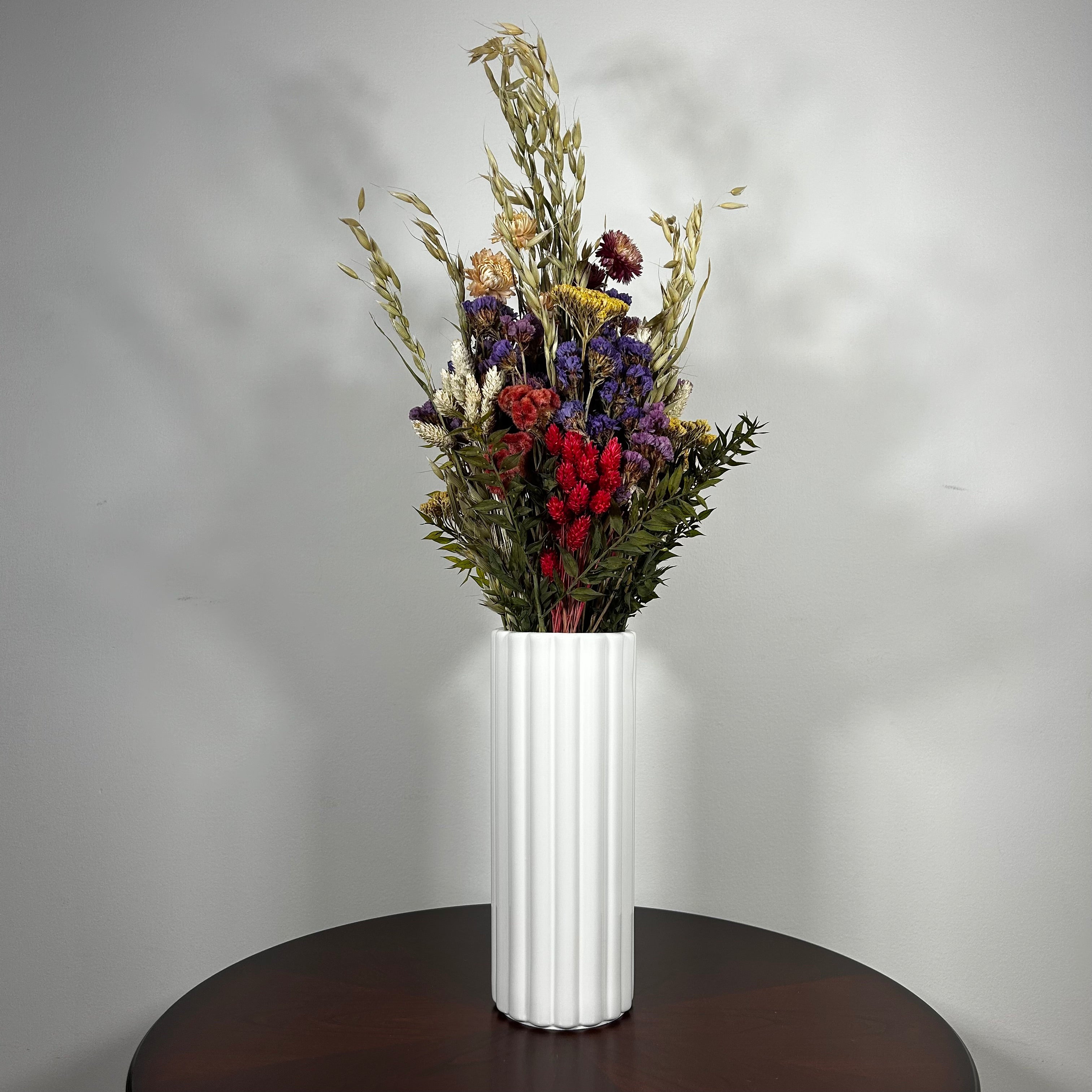 This magnificent, hand-tied bouquet is a vibrant symphony of contrasting colours and textures designed for the sophisticated interior. Seen here in a vibrant white ceramic vase. 