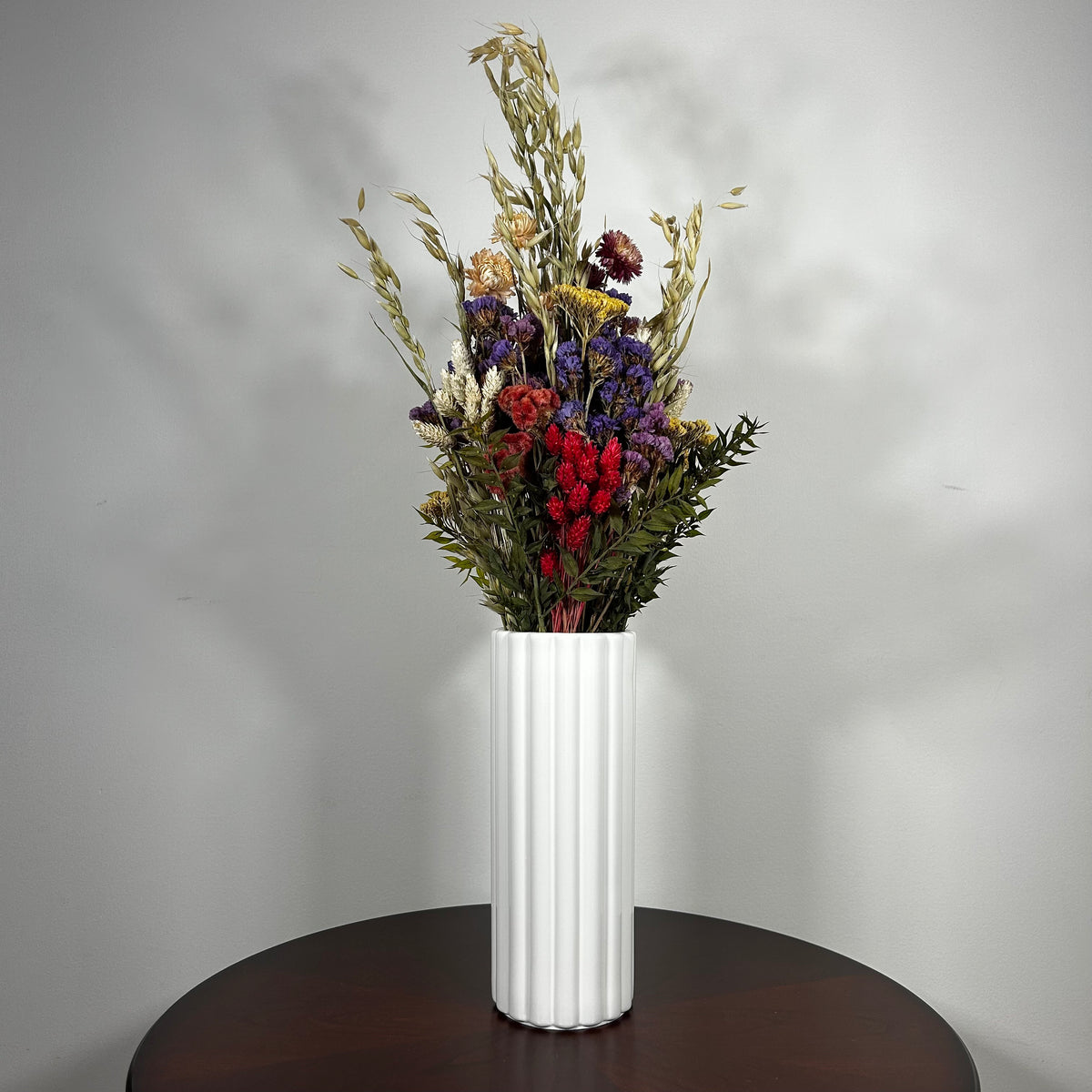 This magnificent, hand-tied bouquet is a vibrant symphony of contrasting colours and textures designed for the sophisticated interior. Seen here in a vibrant white ceramic vase. 