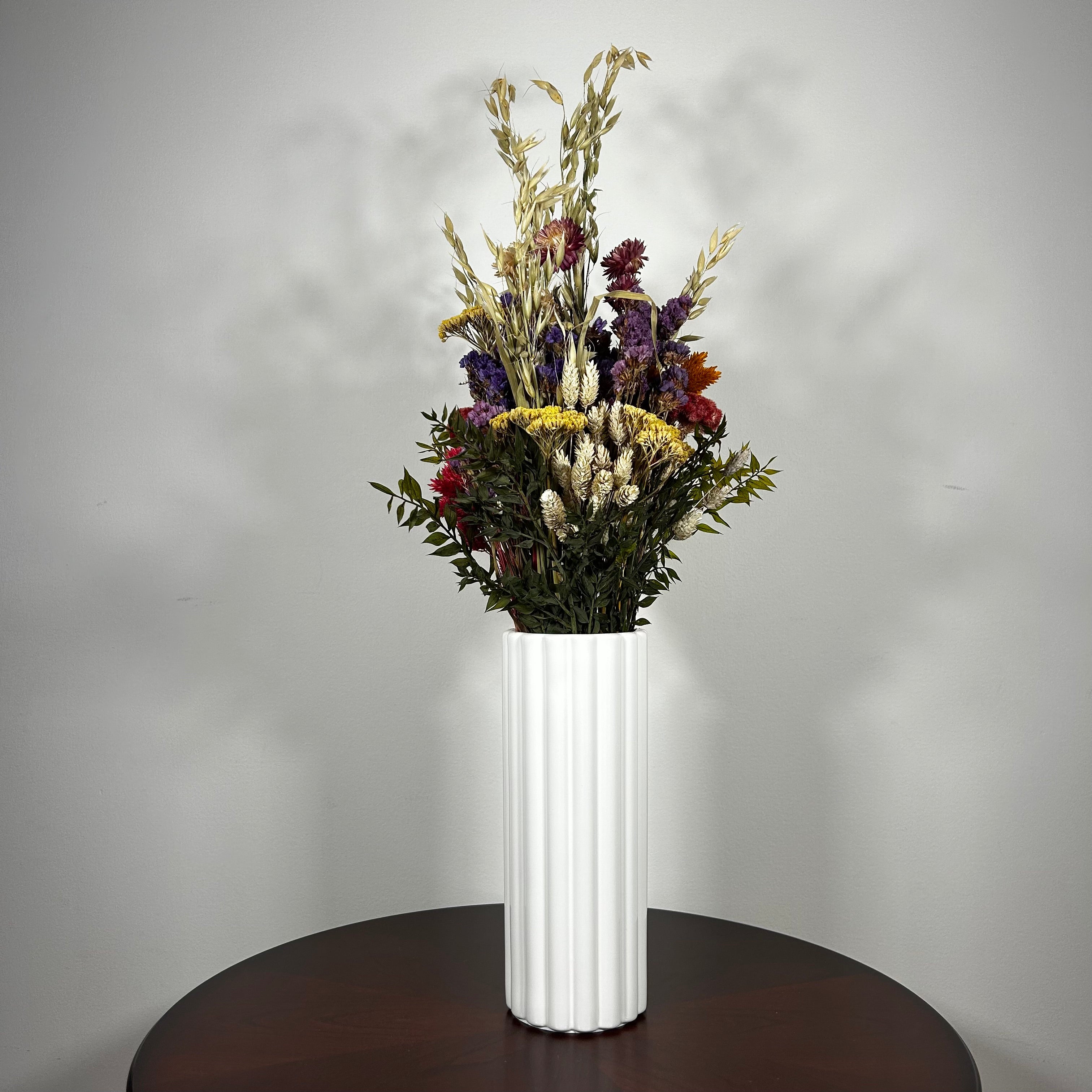 This magnificent, hand-tied bouquet is a vibrant symphony of contrasting colours and textures designed for the sophisticated interior. Seen here in a vibrant white ceramic vase. 