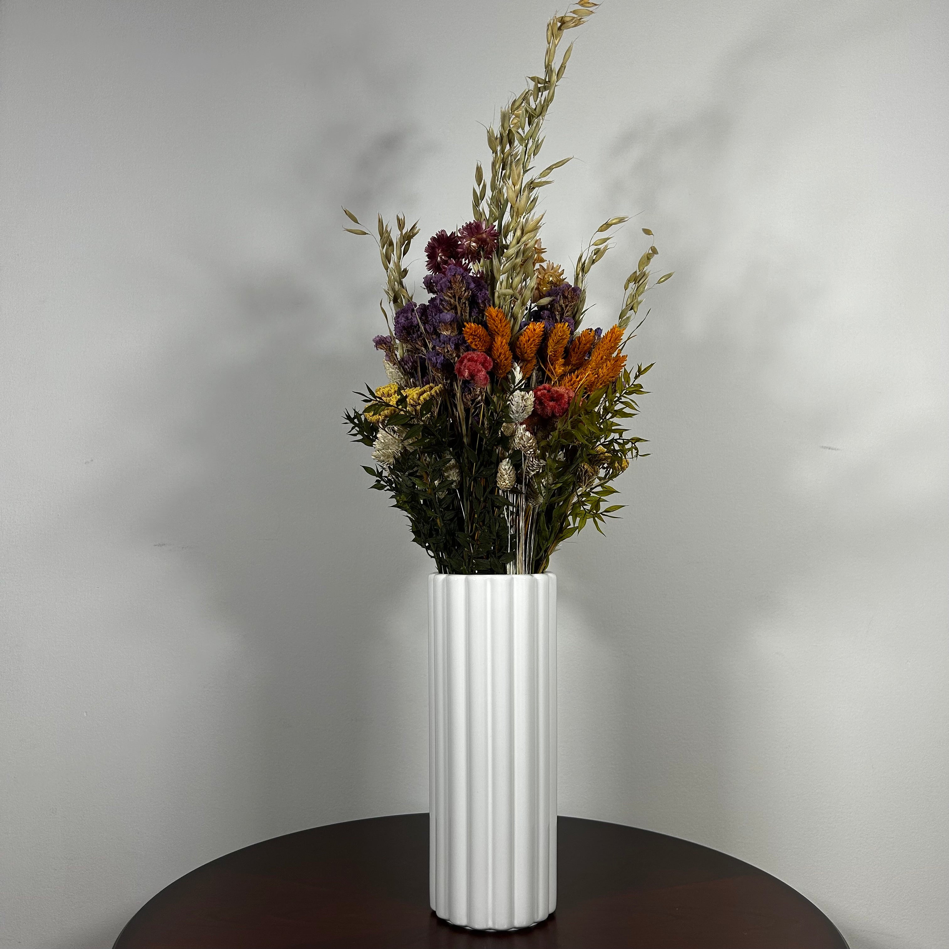 This magnificent, hand-tied bouquet is a vibrant symphony of contrasting colours and textures designed for the sophisticated interior. Seen here in a vibrant white ceramic vase. 