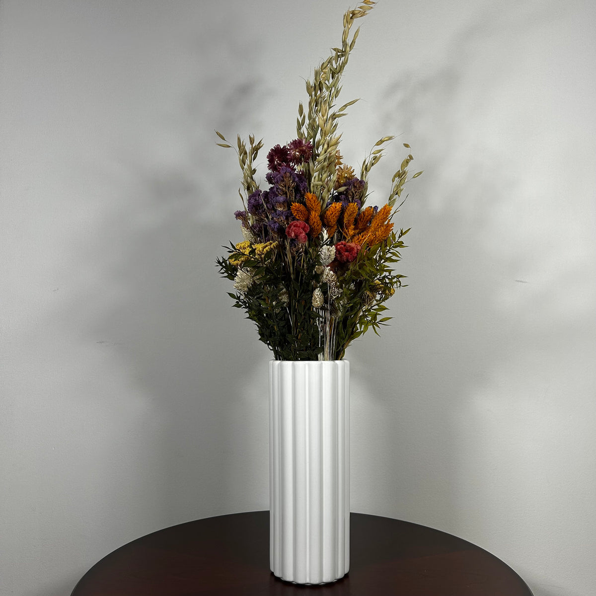 This magnificent, hand-tied bouquet is a vibrant symphony of contrasting colours and textures designed for the sophisticated interior. Seen here in a vibrant white ceramic vase. 