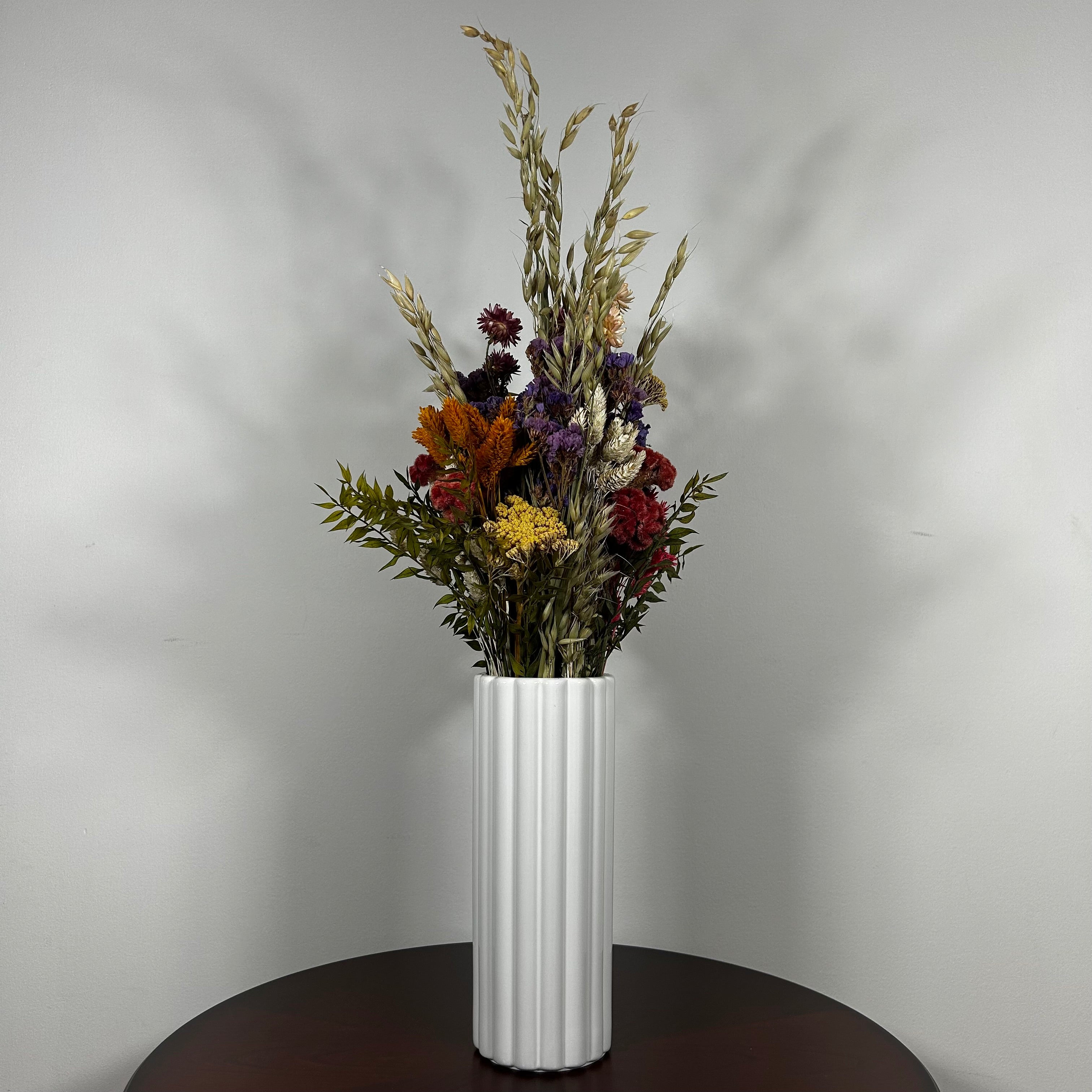 This magnificent, hand-tied bouquet is a vibrant symphony of contrasting colours and textures designed for the sophisticated interior. Seen here in a vibrant white ceramic vase. 