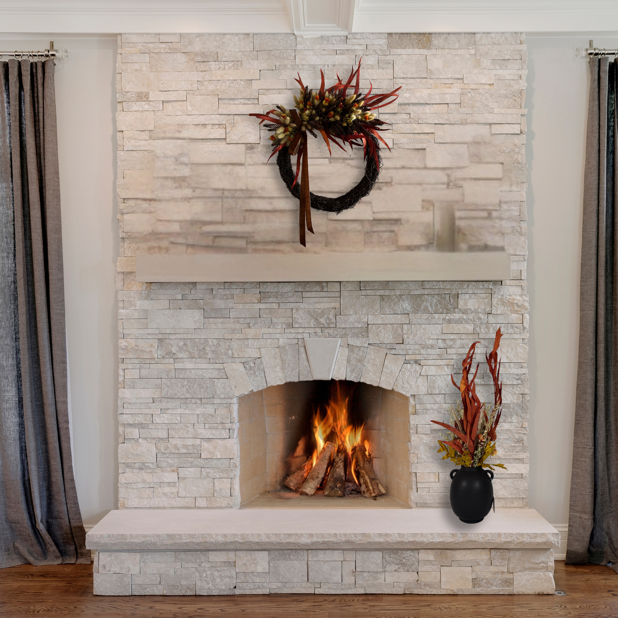 Fireplace with stone surround showcasing a decorative asymmetrical wreath that blends rustic textures with rich autumnal colours, accented with a rich brown velvet ribbon along with a coordinated autumn dried floral arrangement in a rich brown urn shaped vase.