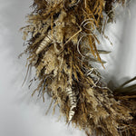 A dried floral arrangement featuring pampas grass, small beige berries, striped dried stems, and curled white wire accents, photographed against a plain light gray background.