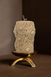 Decorative candle with sunflower patterns on a brass tripod pillar candle holder against a brown background