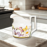 Decorative creamer with floral and butterfly design on a kitchen counter.